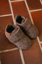 Baby Wool Camel – Chaussons bébé en laine – Bisgaard : deux chaussons sur un sol carrelé.
