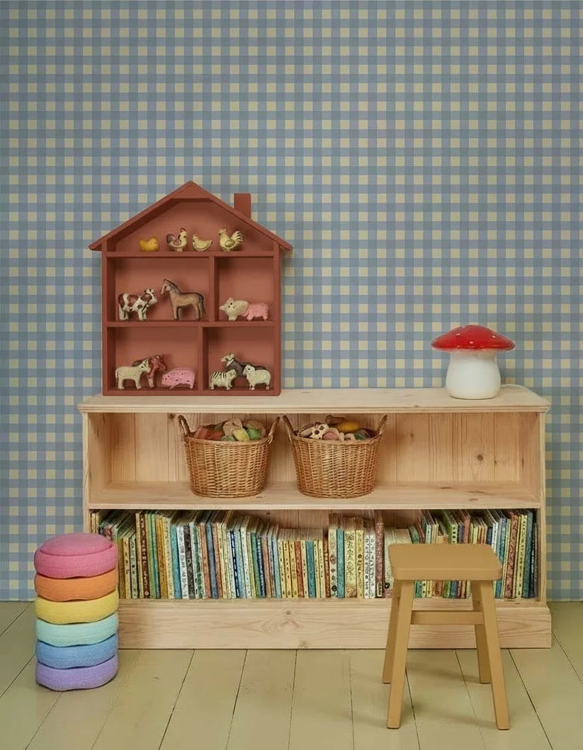 Gingham Ruiten Lichtblauw – Atelier Chien: behang achter een houten kast met boeken en speelgoed.