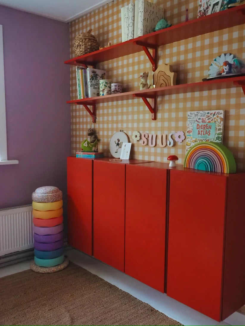 Ochre Yellow Gingham wallpaper by Atelier Chien behind a red cabinet and wall shelves.