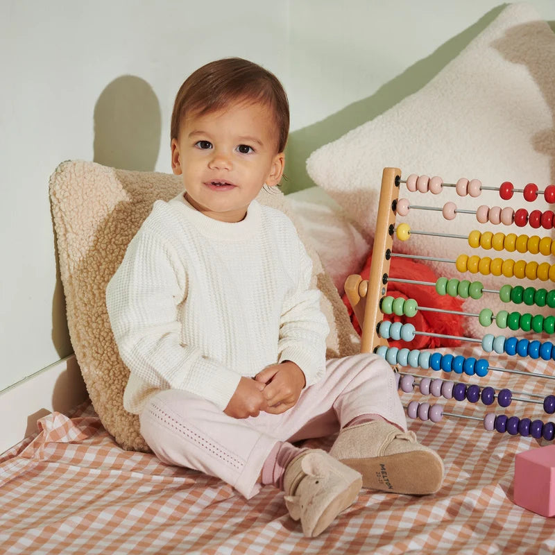 Mouse Wool Slippers – Chaussons pour enfant en laine avec semelle en suède – MELTON : bébé assis parmi des jouets avec les chaussons aux pieds.