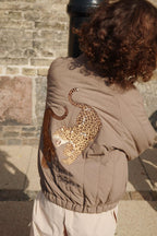 Veste thermique Juno Bomber – Walnut – Konges Sløjd : détail de l'illustration de léopard au dos du blouson bomber porté.