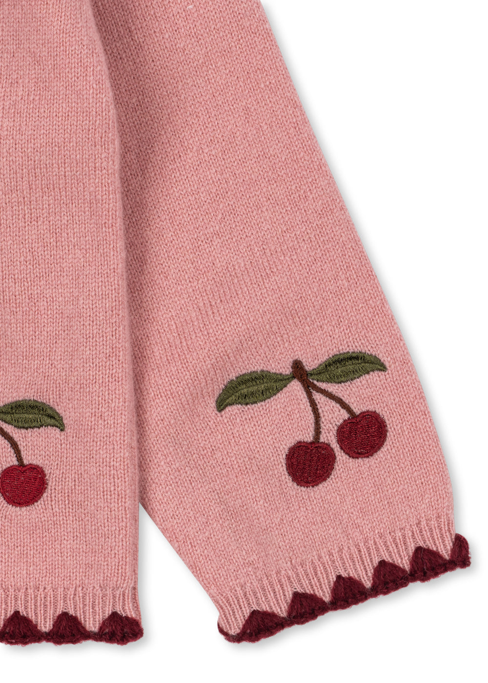Wollen vest Collette – Pale Blush – Konges Sløjd: detail van de roze mouw met kersen en donkere boord.