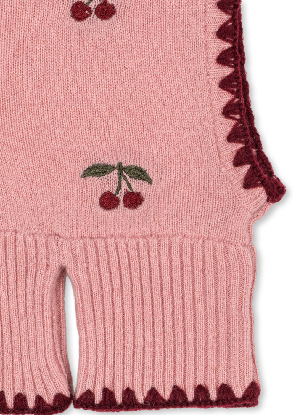 Woll-Balaclava Collette – Pale Blush – Konges Sløjd: Detail der Kirschen, des dunklen Saums und des Rippbündchens der Balaclava.